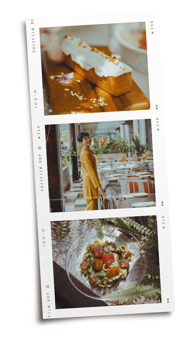 A strip of three photographs. The first photo shows a dessert with white icing on a wooden board, garnished with edible flowers and white sprinkles. The second photo features a woman in a yellow outfit smiling and standing in a well-lit restaurant with large windows and a modern interior. The third photo displays a bowl of colorful chopped vegetable salad with cherry tomatoes, carrots, and greens, placed outdoors among ferns.