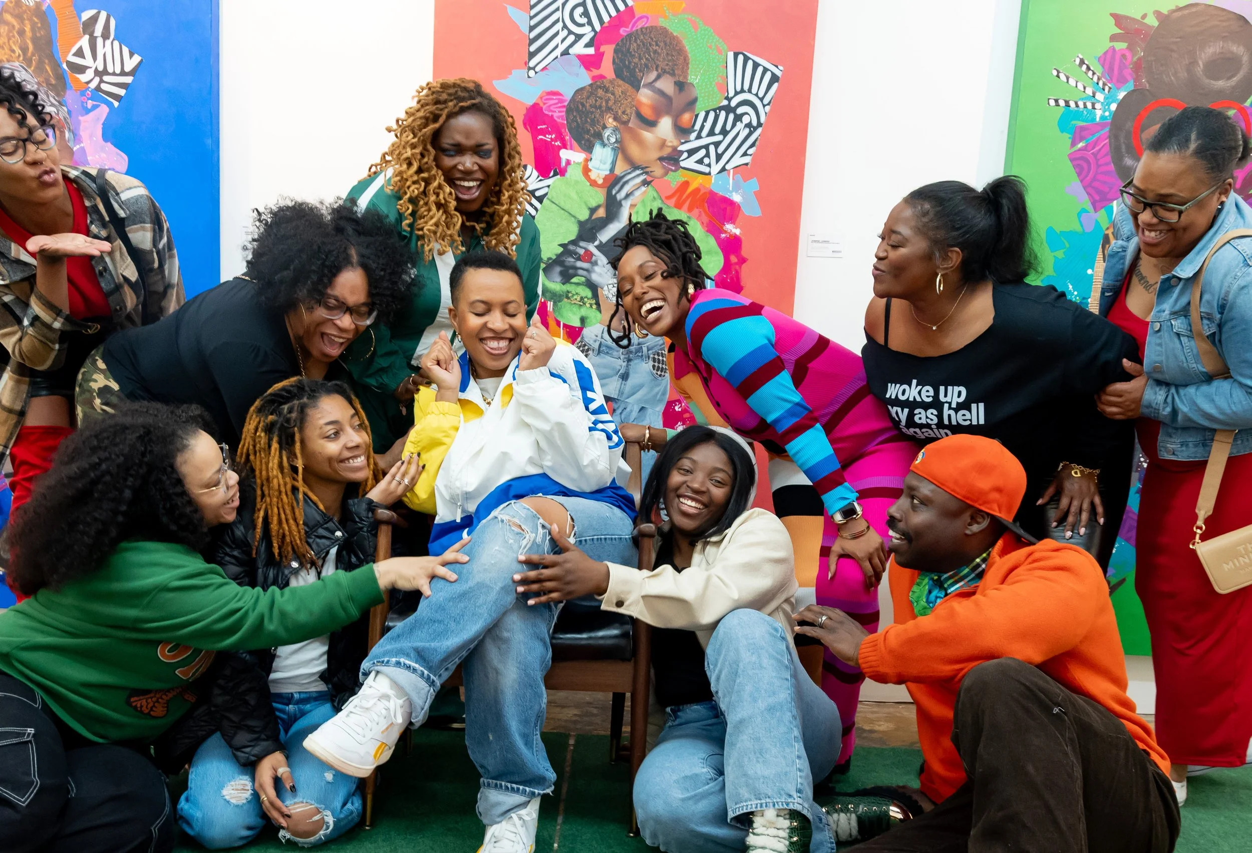 Group of diverse women laughing and enjoying together in an art gallery with colorful artwork in the background.