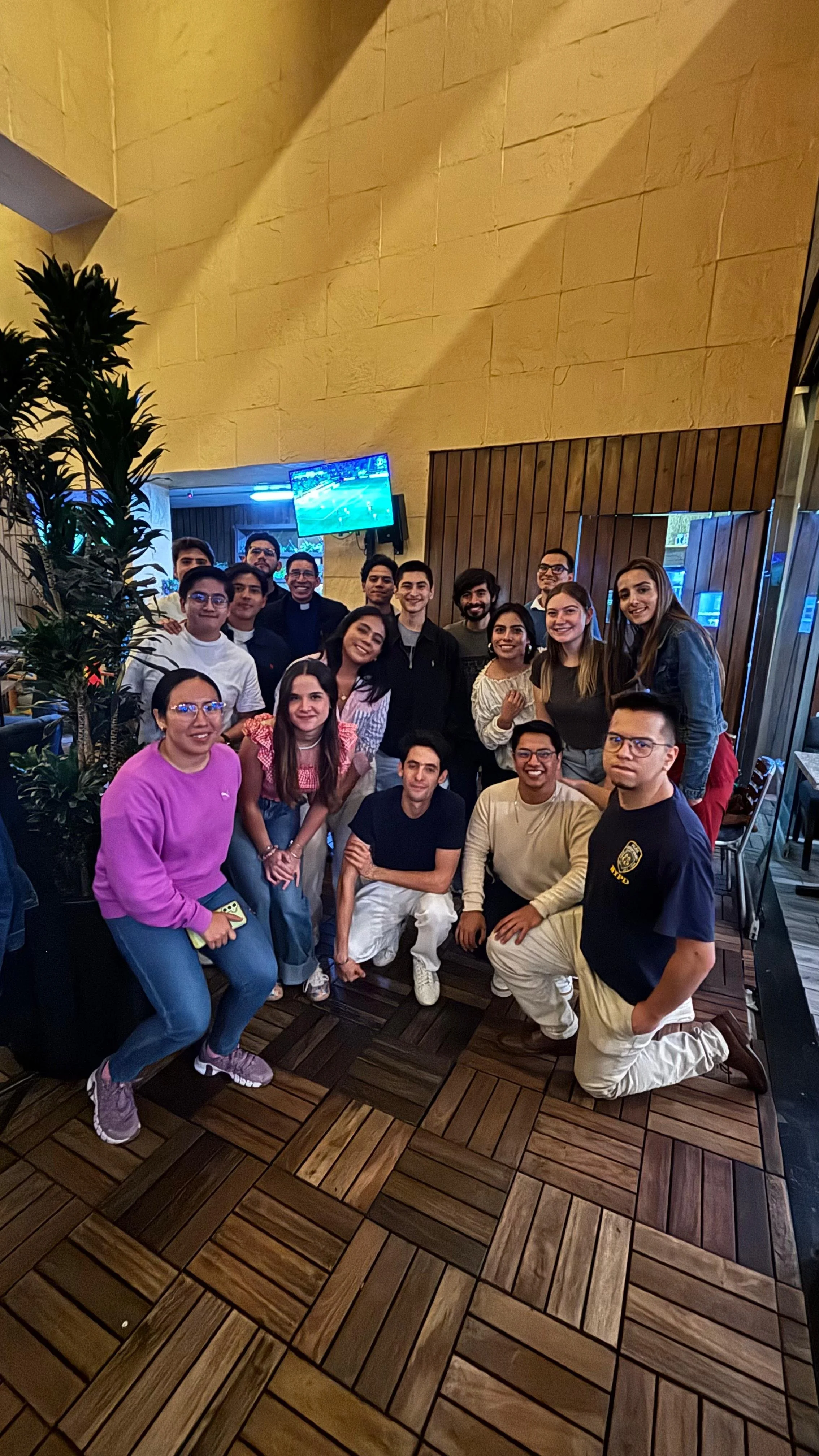 Grupo de personas posando en un restaurante, algunos están agachados y otros de pie, todos sonriendo. FEF Universitarios Puebla.