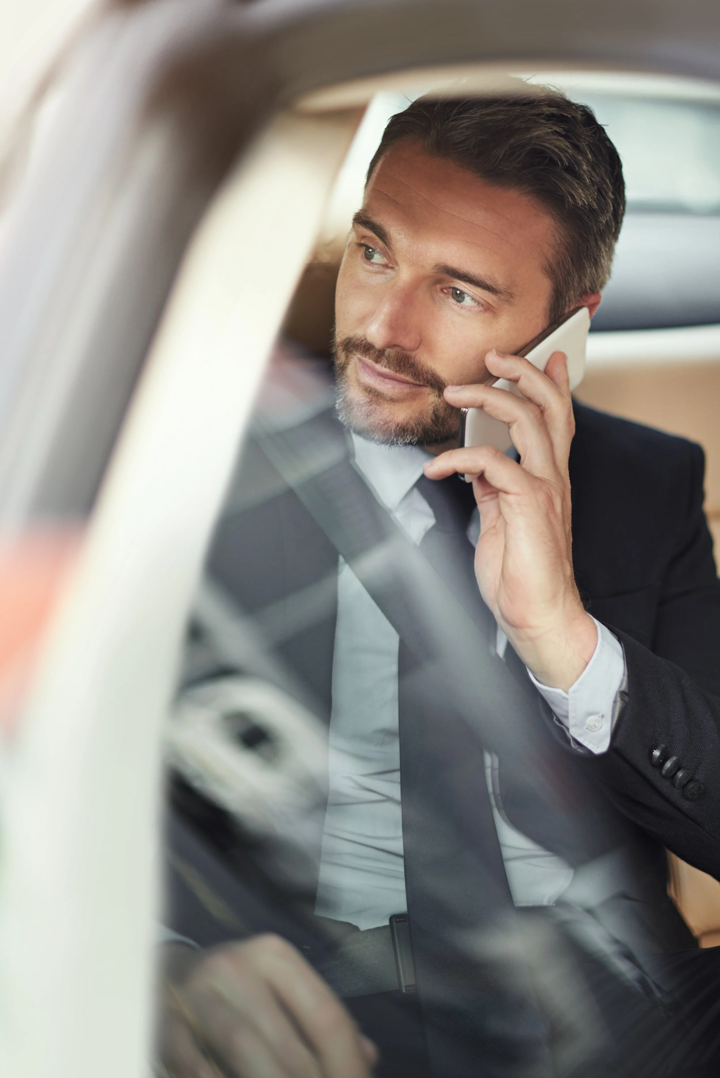Executive chauffeur service with business traveler on phone in a luxury car
