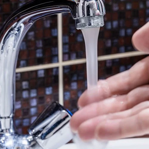 A man running his hand under hot water.
