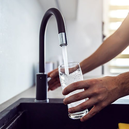 A man filling a glass with clean water.