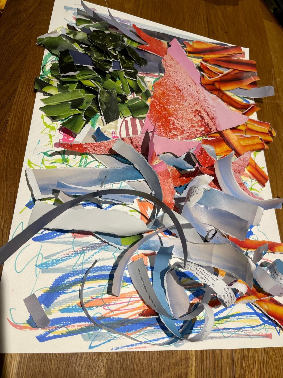 Mixed collage of torn paper scraps, including green, gray, pink, white, and orange, arranged on a white sheet with colorful scribbles and drawings.