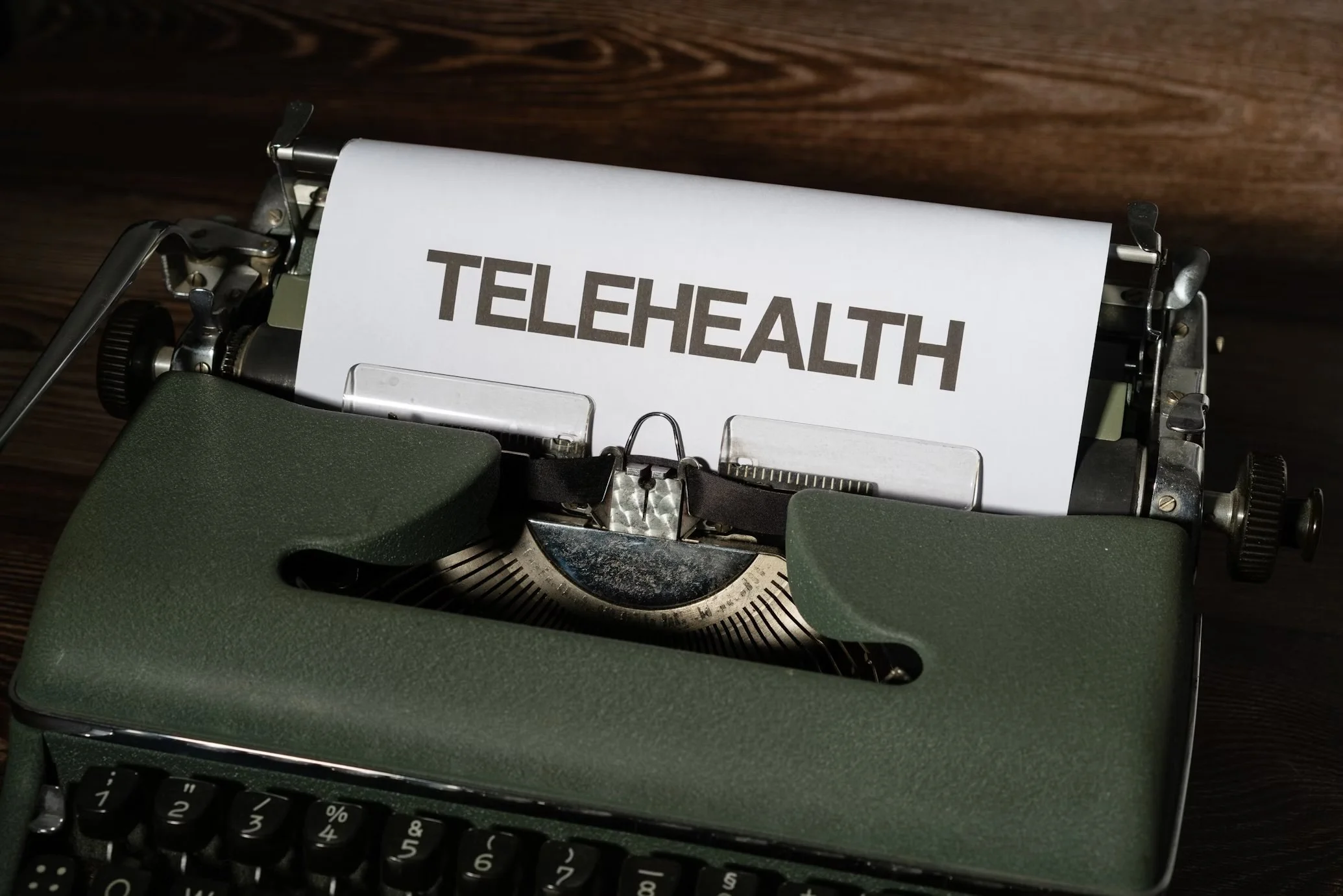 Typewriter with a paper that has the word 'TELEHEALTH' printed on it.