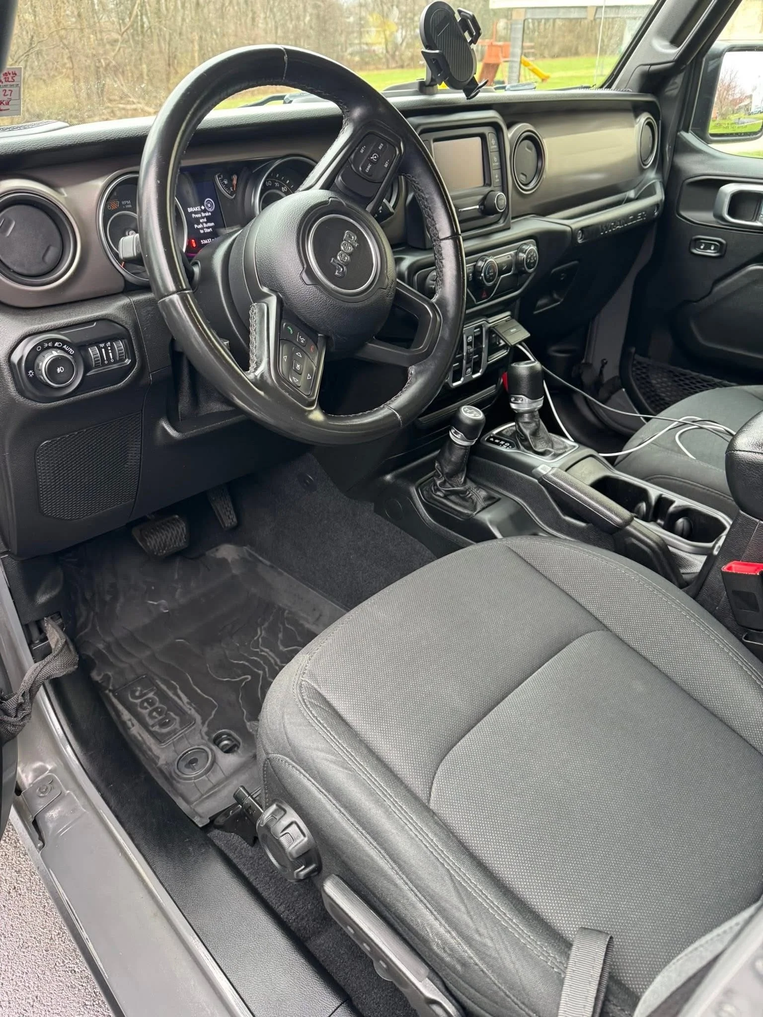 Interior of a Jeep vehicle showing the steering wheel, dashboard, gear shifter, and front passenger seat.