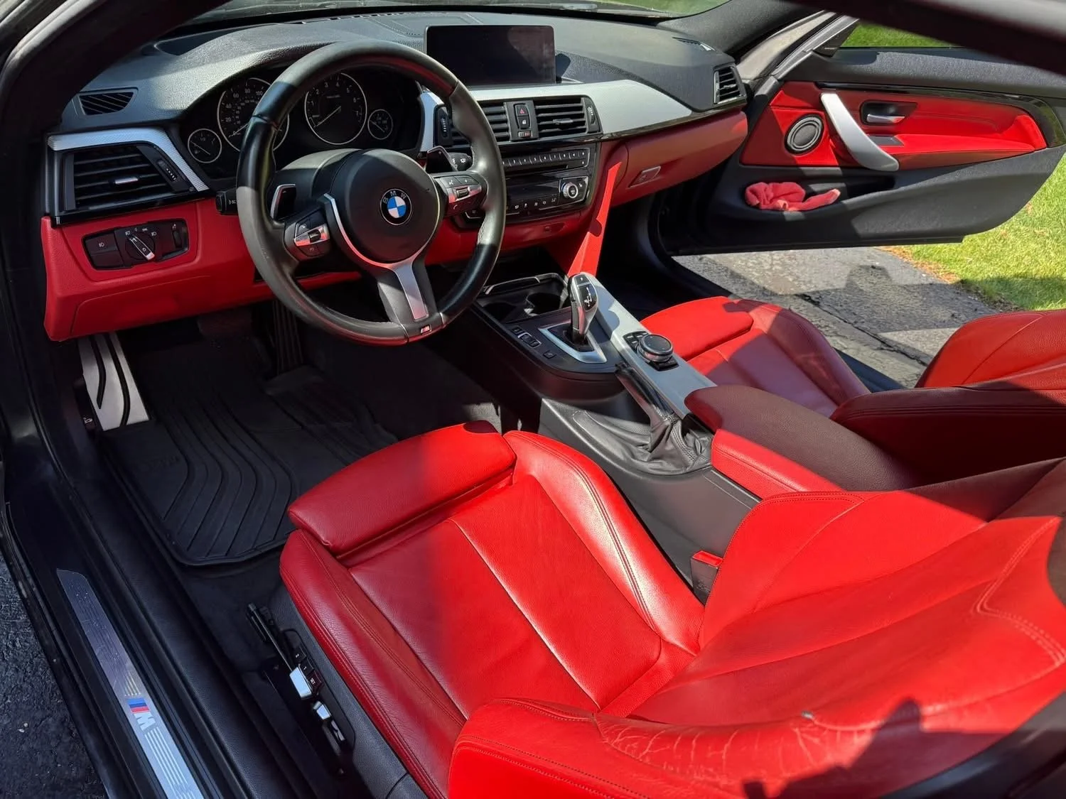 Interior of a BMW car with red leather seats, black dashboard, and a gear shift lever in the center console.