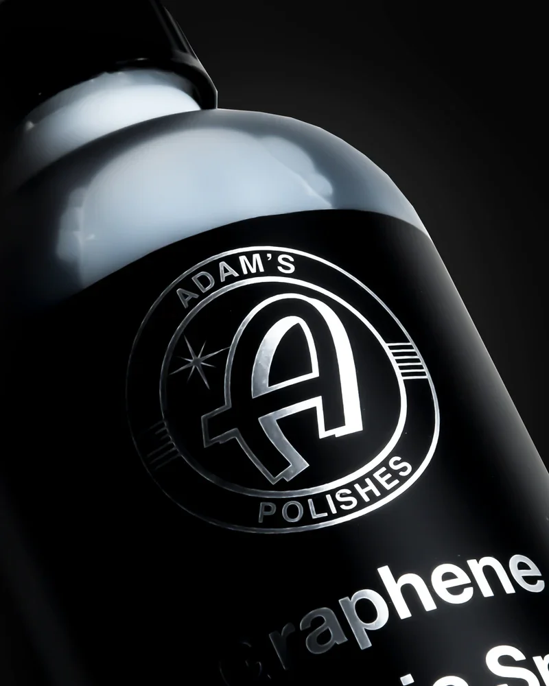 Close-up of a black bottle labeled 'Adam's Polishes' with a silver logo and the word 'Grapheme' visible.