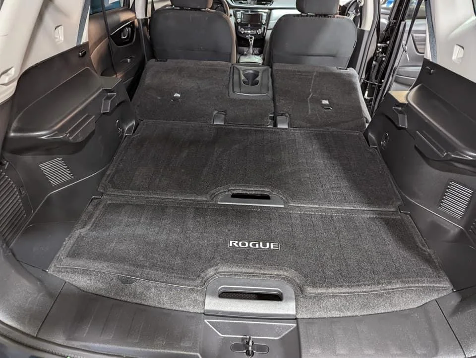 The interior of a vehicle with the rear seats folded down, showing a large flat cargo area with a black Rugged Ridge mat.