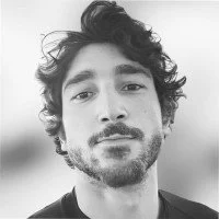 Close-up black and white photo of a man with curly hair and a beard