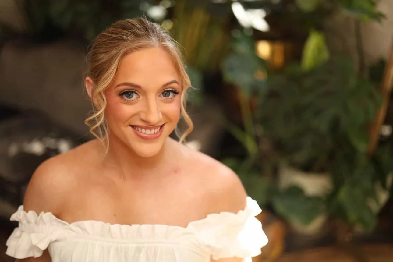 Bride smiling in strapless gown with radiant makeup and soft curled hairstyle at mississippi wedding venue