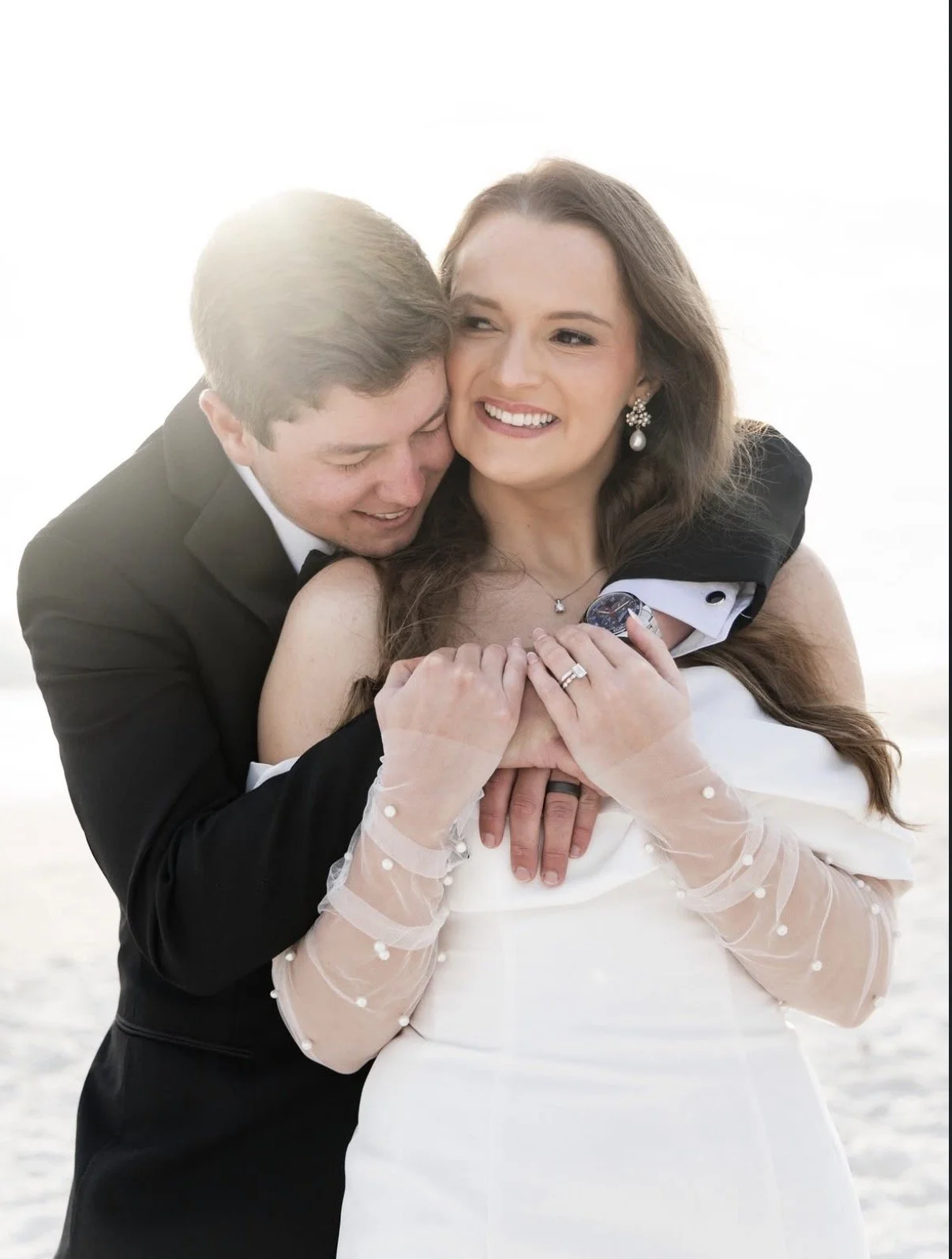 A couple dressed in wedding attire sharing a joyful moment outdoors.