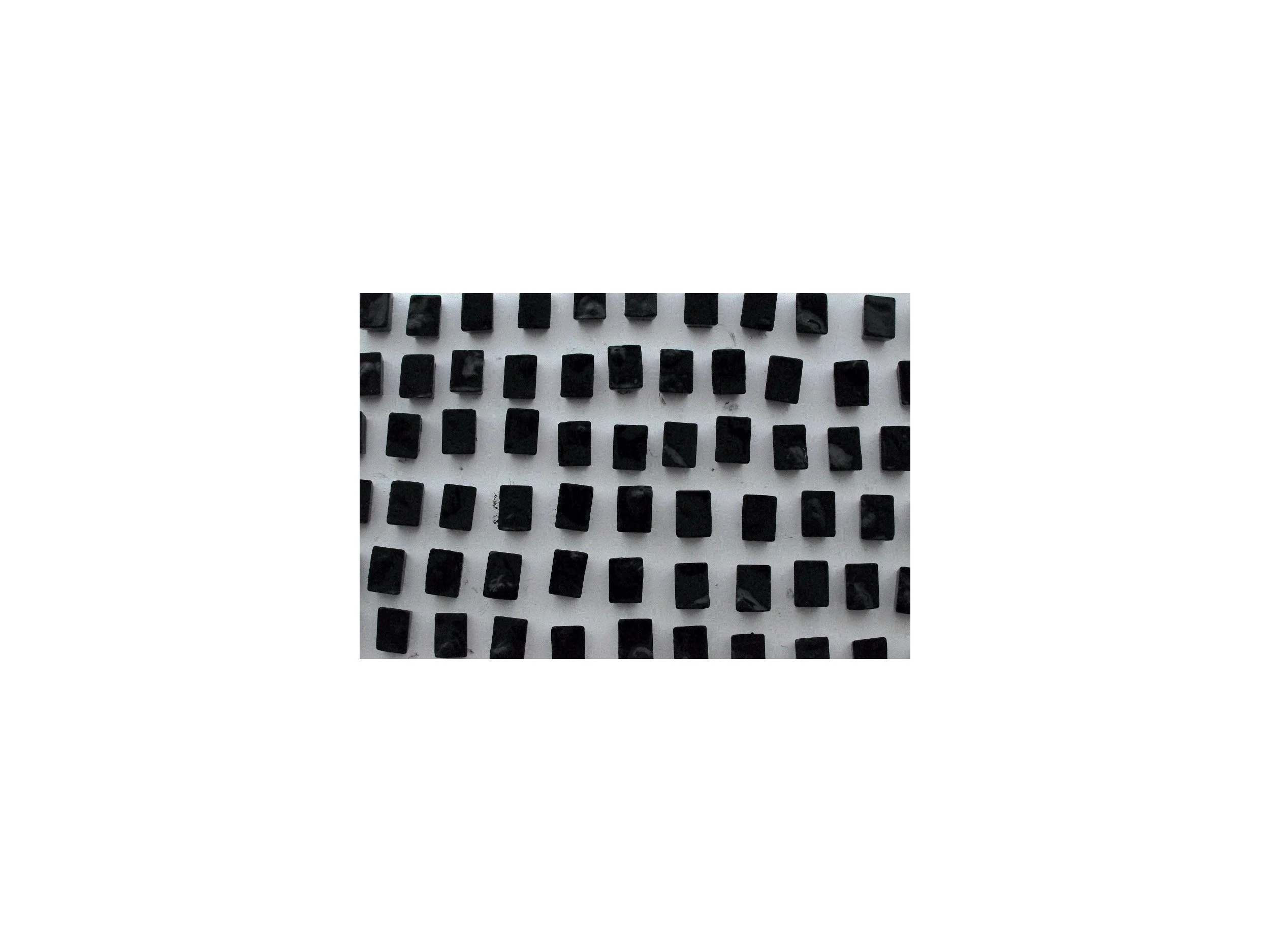 Numerous black, rectangular blocks of a similar size, arranged on a plain white surface.