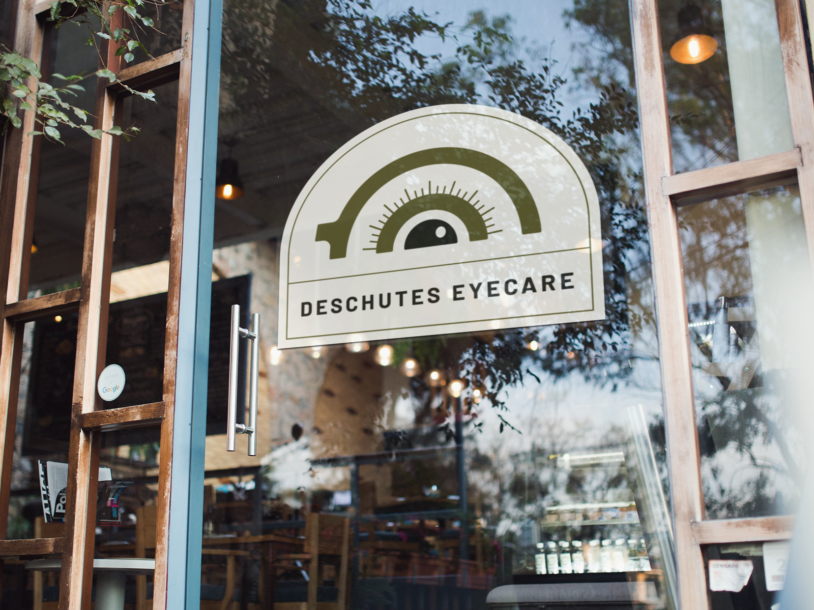Glass door of Deschutes Eyecare with a logo featuring a stylized eye chart and the business name.