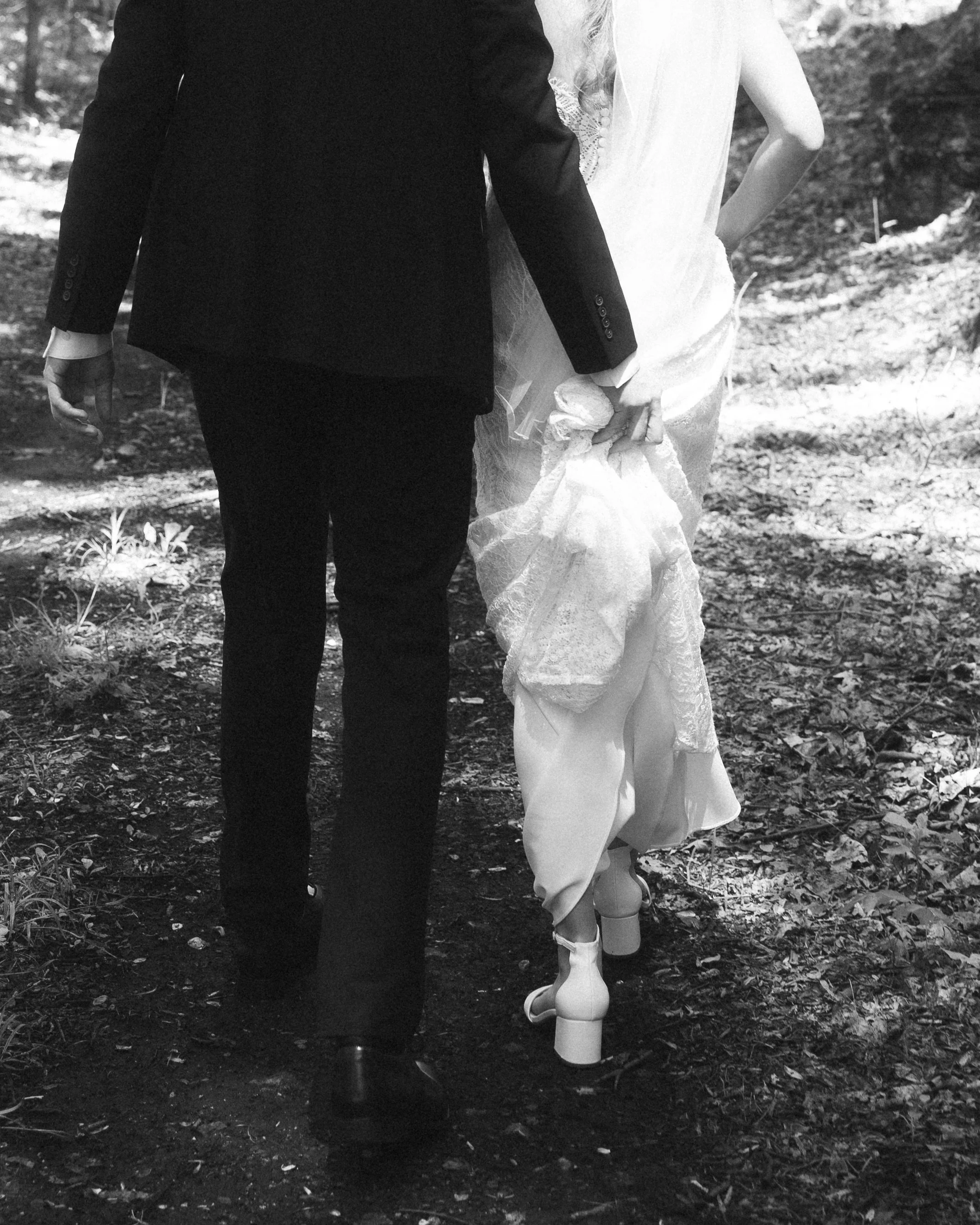 Documentary wedding photograph of a groom holding a brides dress train as they are walking from a southern California wedding