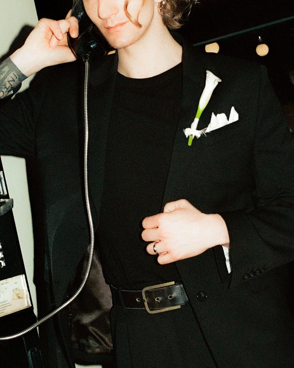 Editorial wedding photograph of a groom holding a payphone to his ear from a California wedding