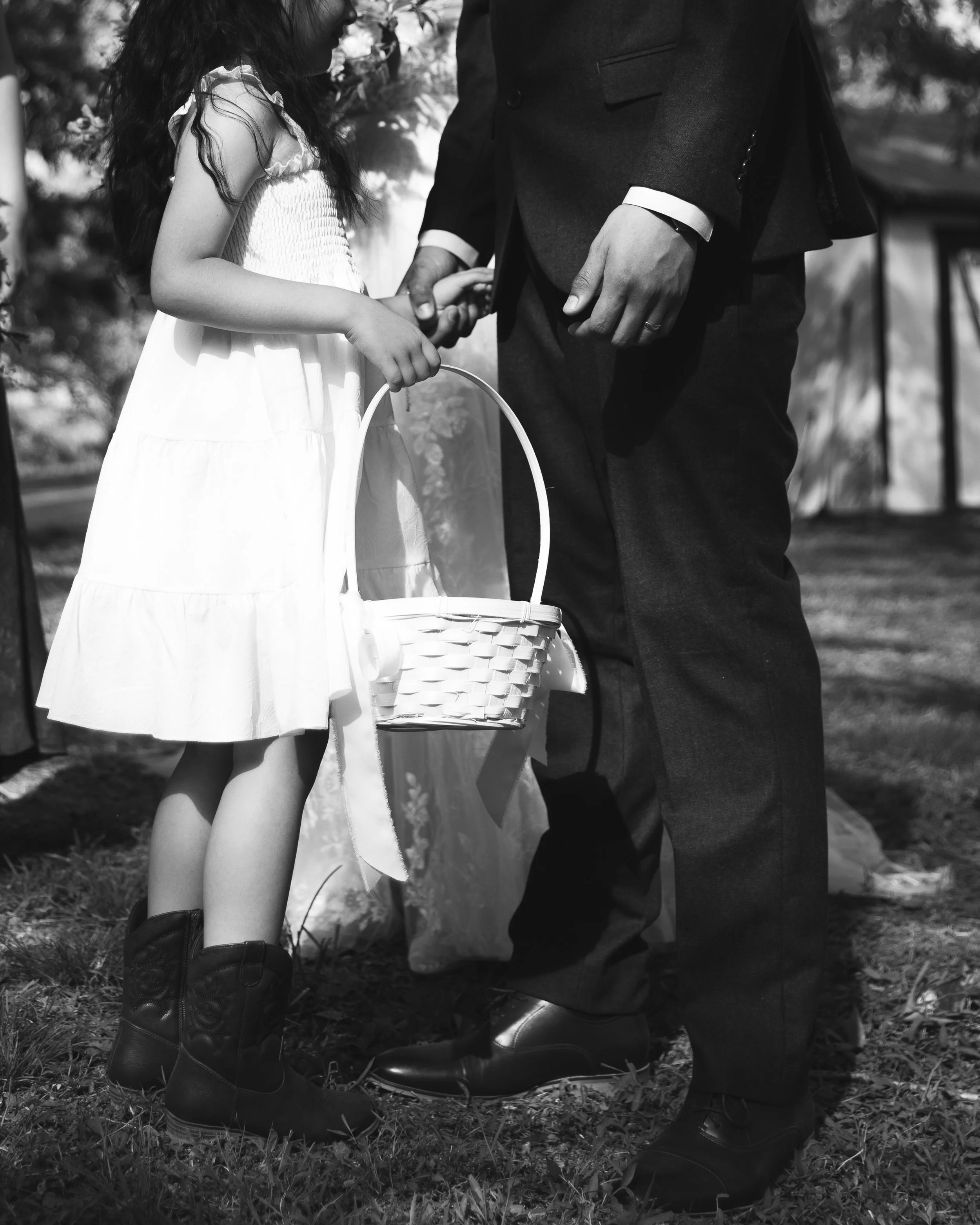 Documentary wedding photograph and a flower girl giving her basket to the groom at a southern California wedding