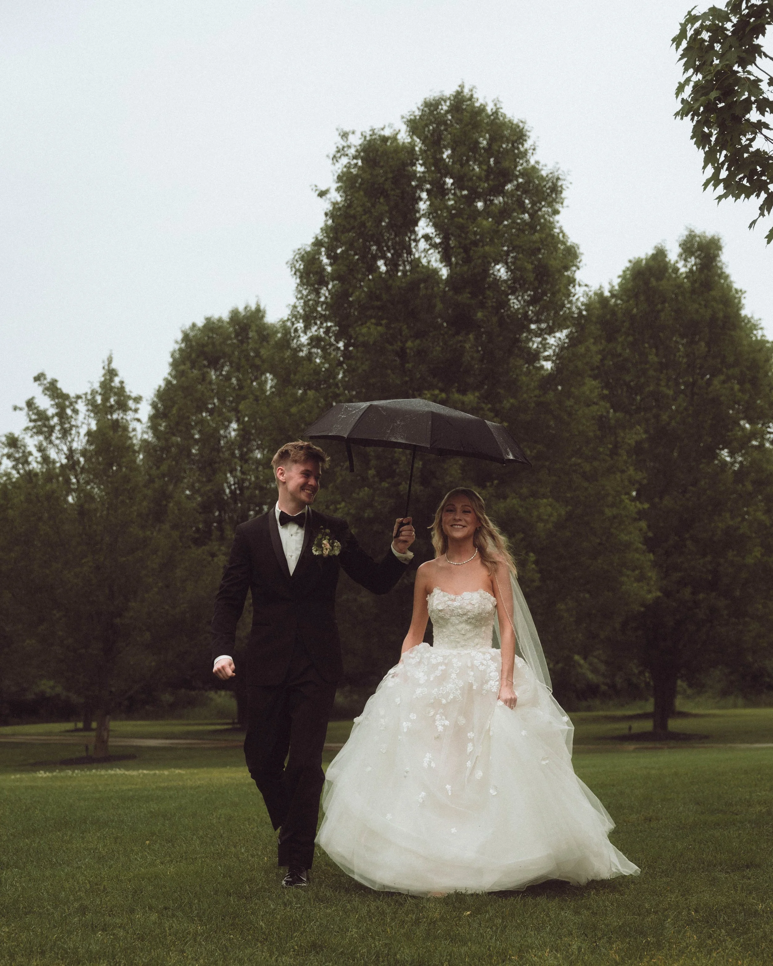 Documentary wedding photograph of a bride and groom walking in the rain with an umbrella in southern California