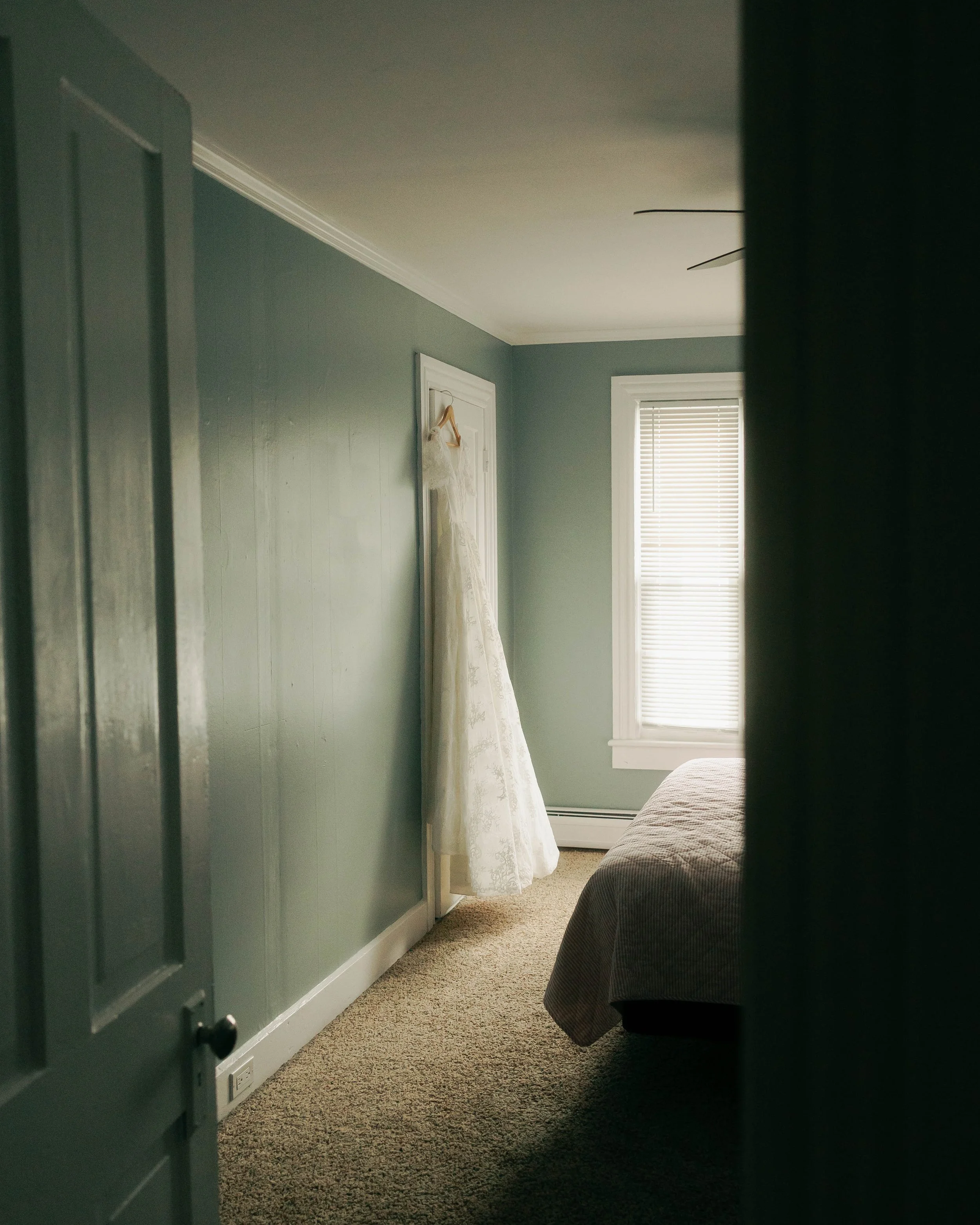 Documentary wedding photograph of a wedding dress hanging in a bedroom in southern California