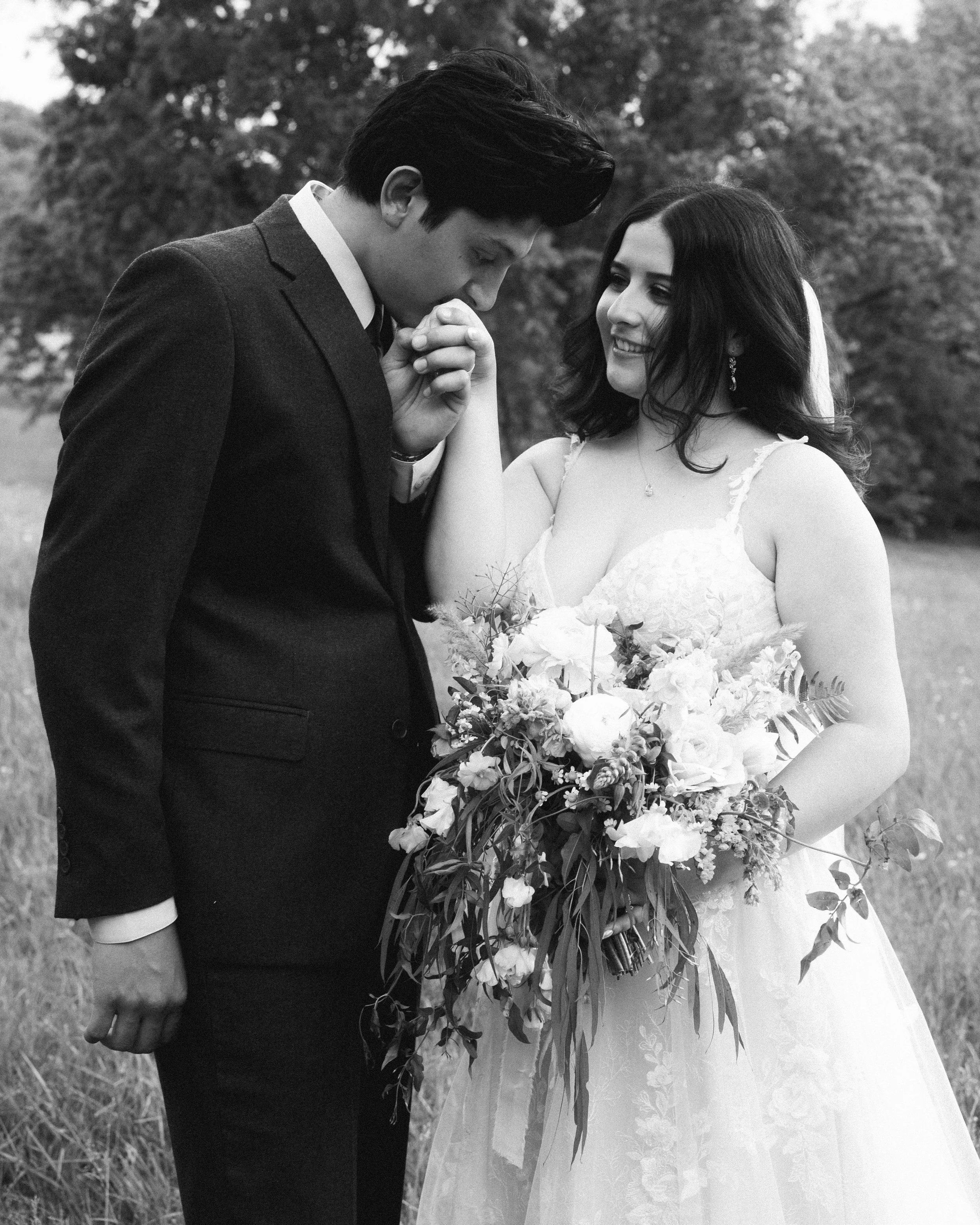 Documentary wedding photograph of a groom kissing his brides hand at a southern California wedding