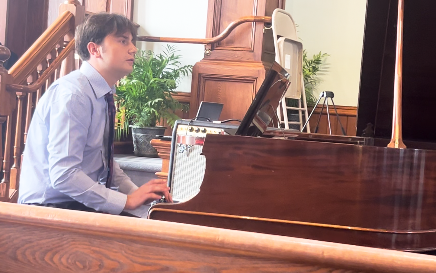 An adult student reading sheet music while performing "River Flows in You" by Yiruma on a grand piano during Lifelong Music School's annual recital.