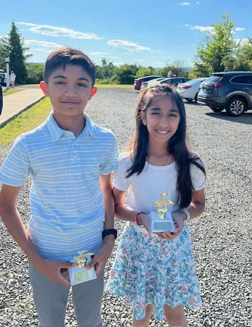 A boy and a girl outside in the parking lot smiling at the camera after their performances at Lifelong Music School's 2024 annual recital.