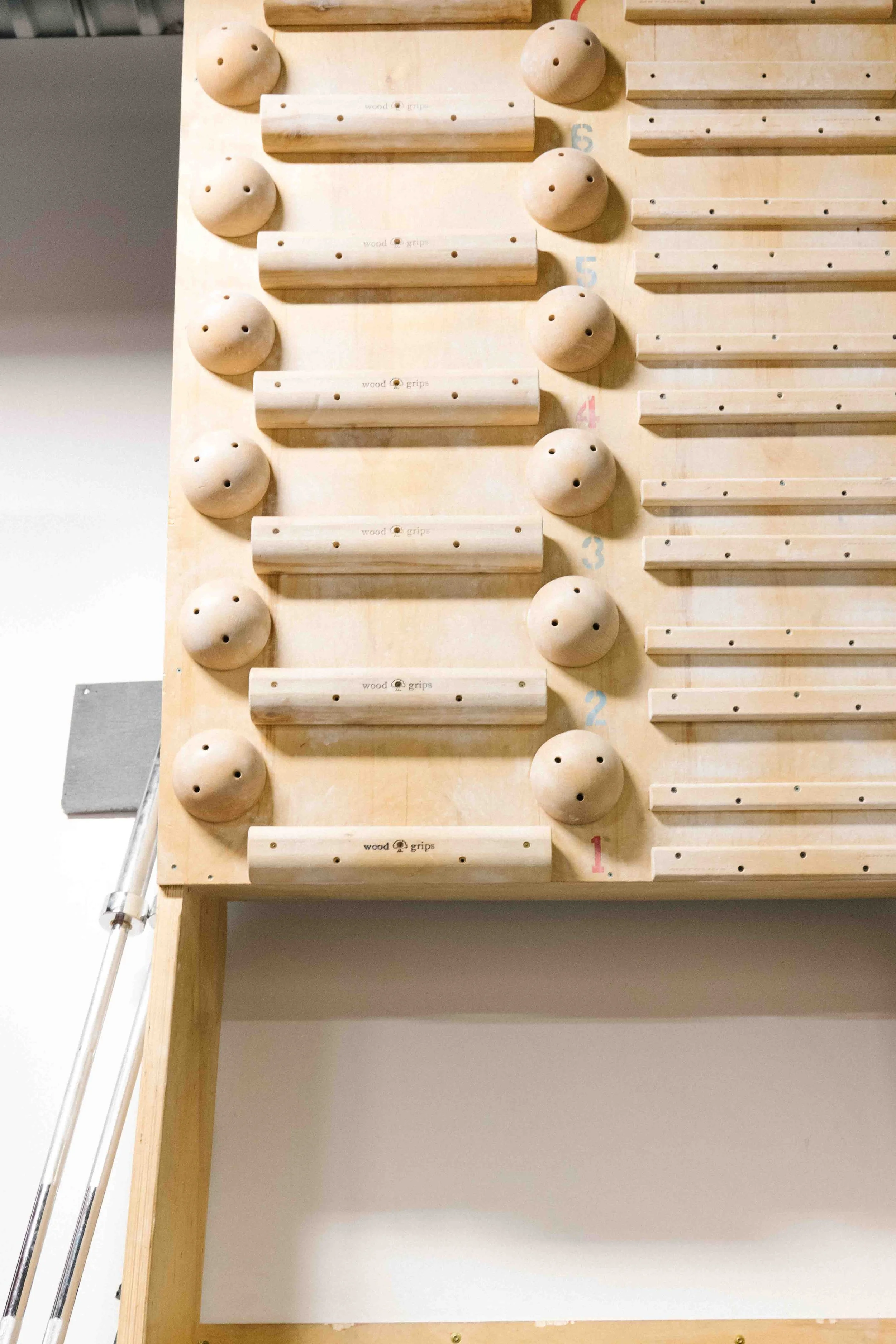 A wooden climbing wall with various circular and rectangular holds, labeled with numbers from 1 to 5, designed for indoor physical activity or training.