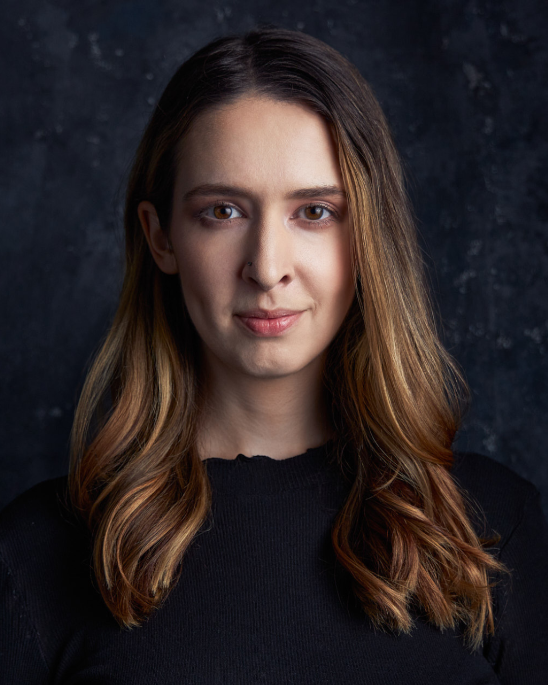 Headshot of a woman with brown hair against a black background