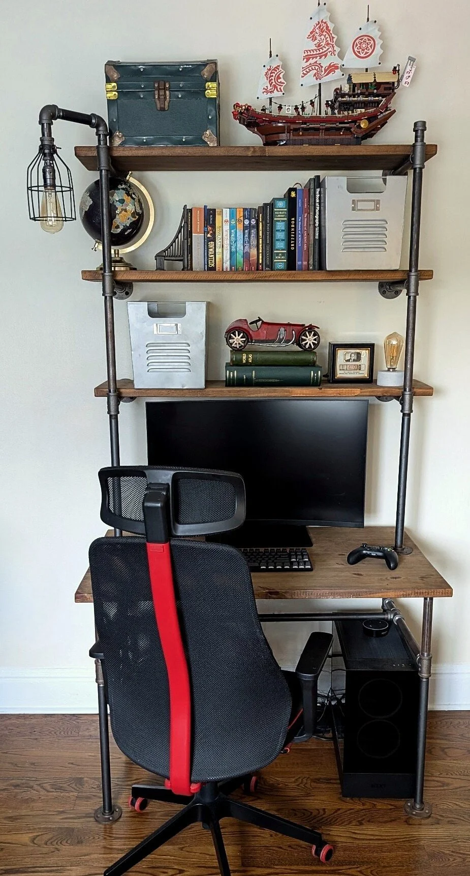 Industrial pipe desk and shelving styled with books, globe, vintage decor, and model ship in a teen bedroom designed by Caroline by Design.