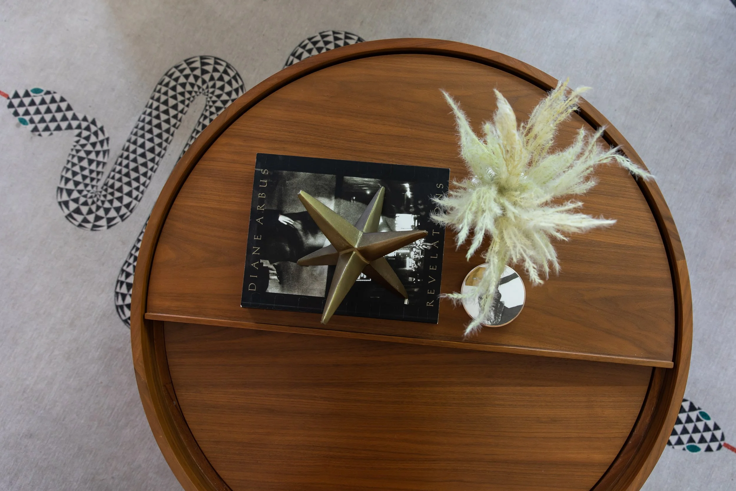 Round wood coffee table styled with decor in a colorful eclectic living room.