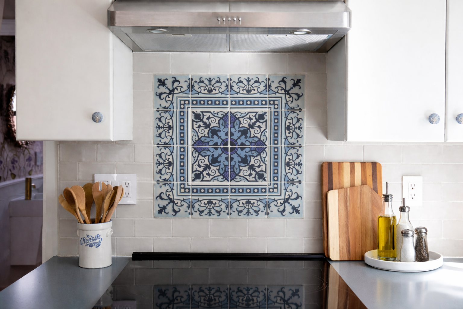A bright, livable kitchen featuring a blue statement backsplash tile, soft gray countertops, warm wood floors, and layered brass accents by Caroline by Design in Montclair, NJ.