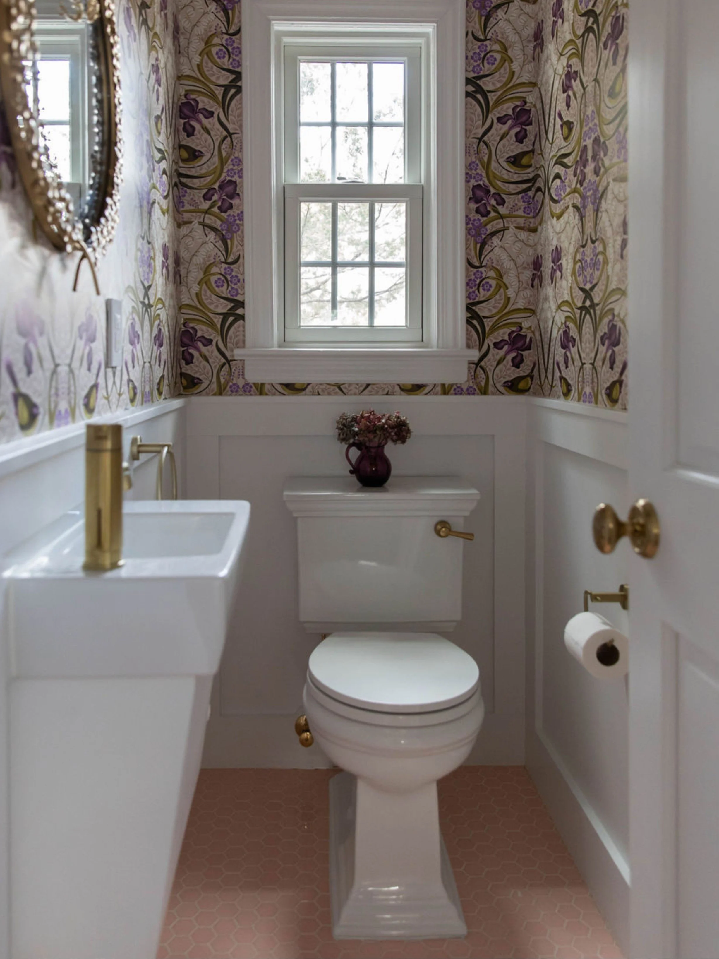 Full view of a botanical powder room with pink hex tile flooring and floral wallpaper.
