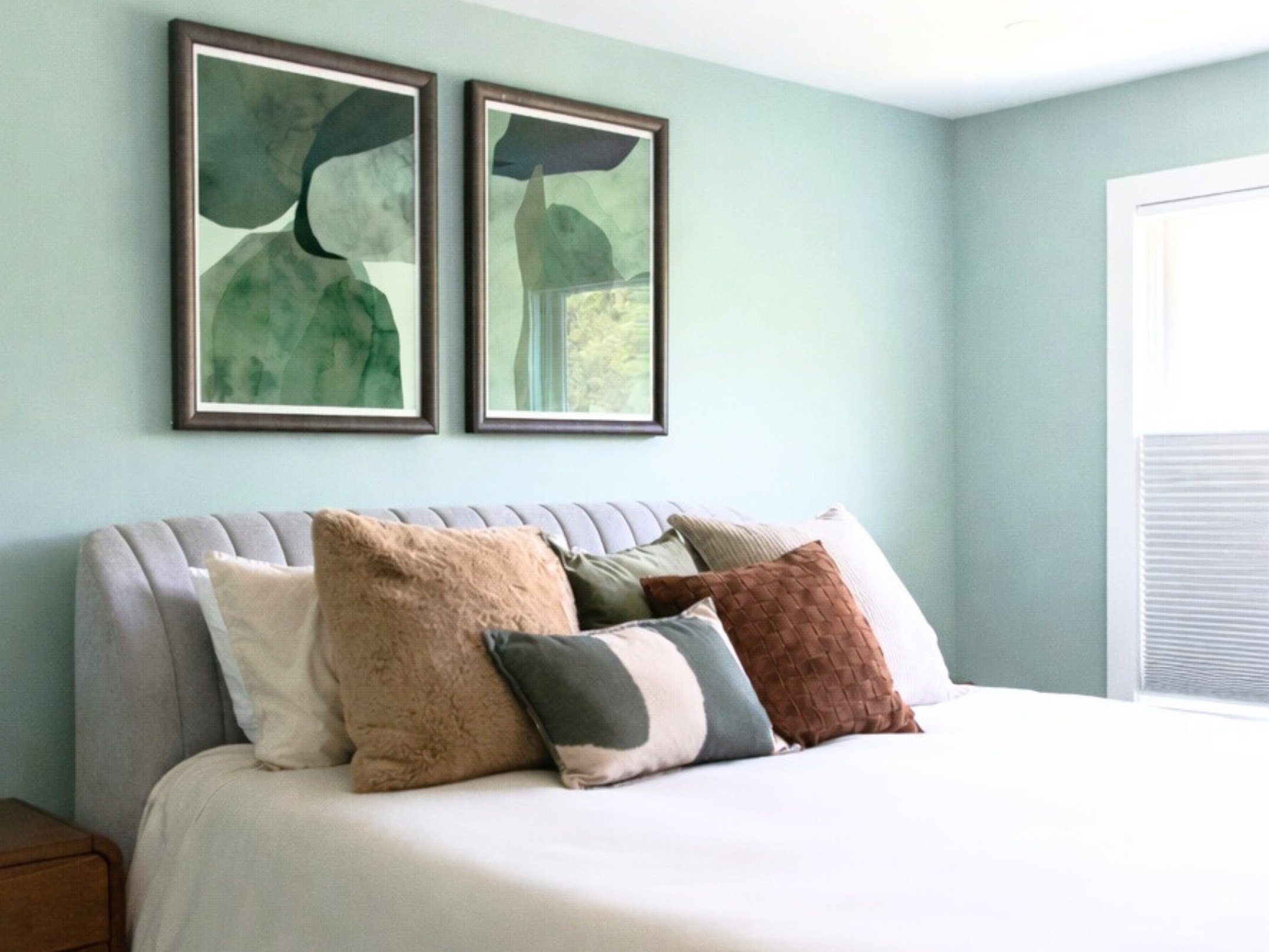 Abstract botanical artwork above upholstered bed in an organic coastal bedroom designed by Caroline by Design in Montclair, NJ.