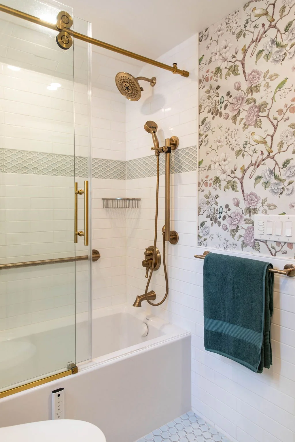 Subway tile shower with brass plumbing fixtures and glass enclosure in a primary bathroom renovation.