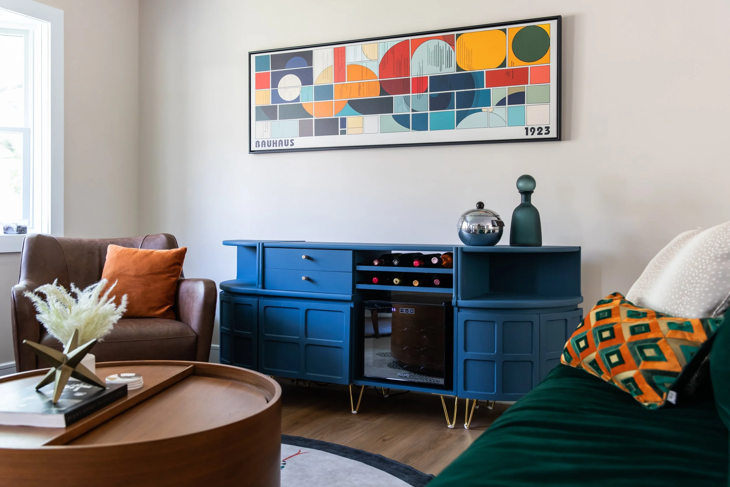 Styled blue sideboard with Bauhaus artwork and decorative accents in an eclectic living room.