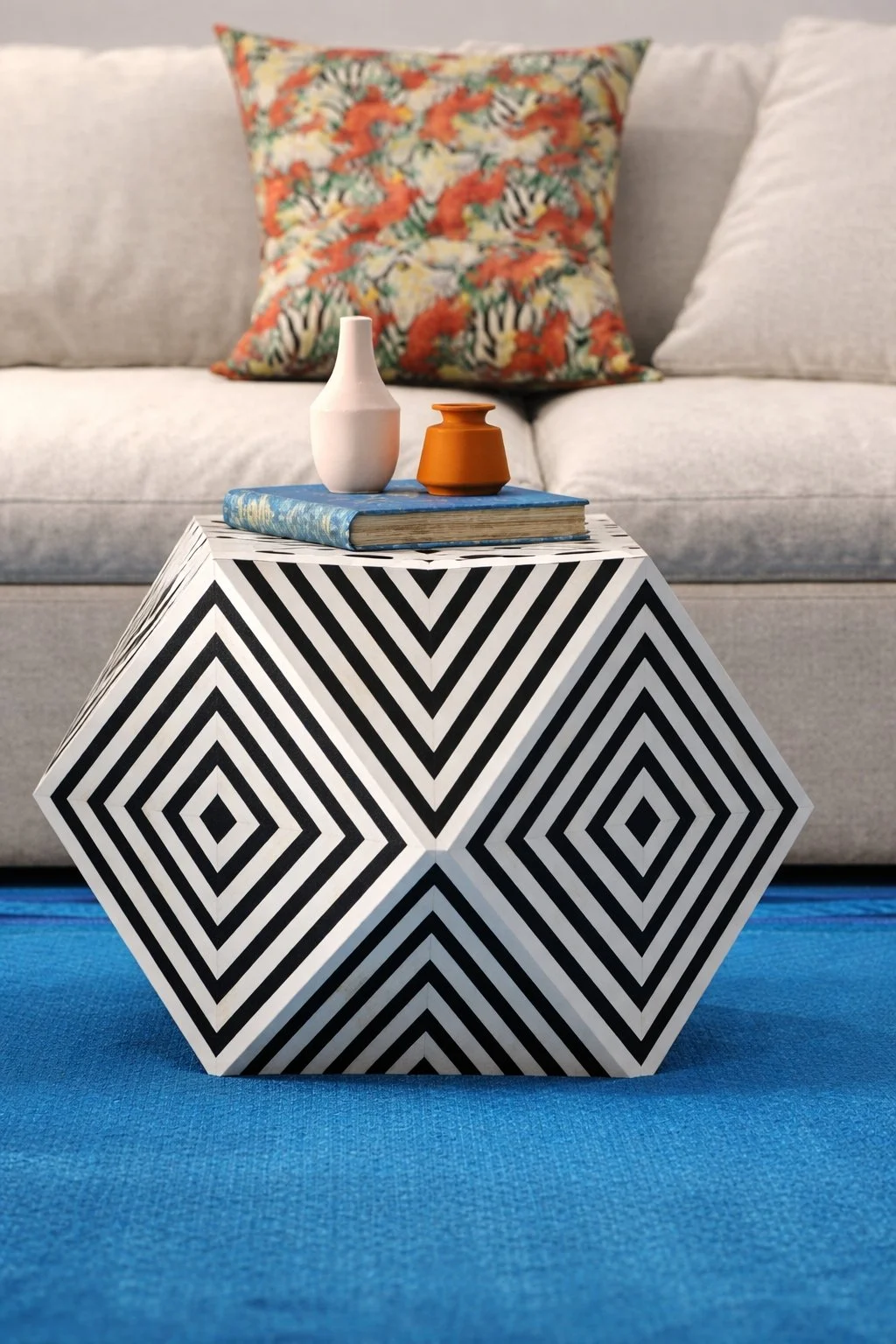 Close-up of black and white geometric ottoman coffee table with styled decor in colorful eclectic living room by Caroline by Design.