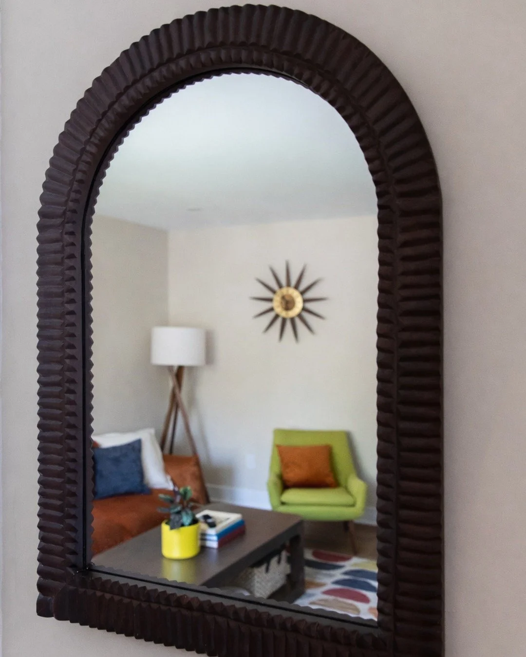 Mirror reflection view of eclectic TV room with orange sofa and colorful accents in Montclair, NJ.