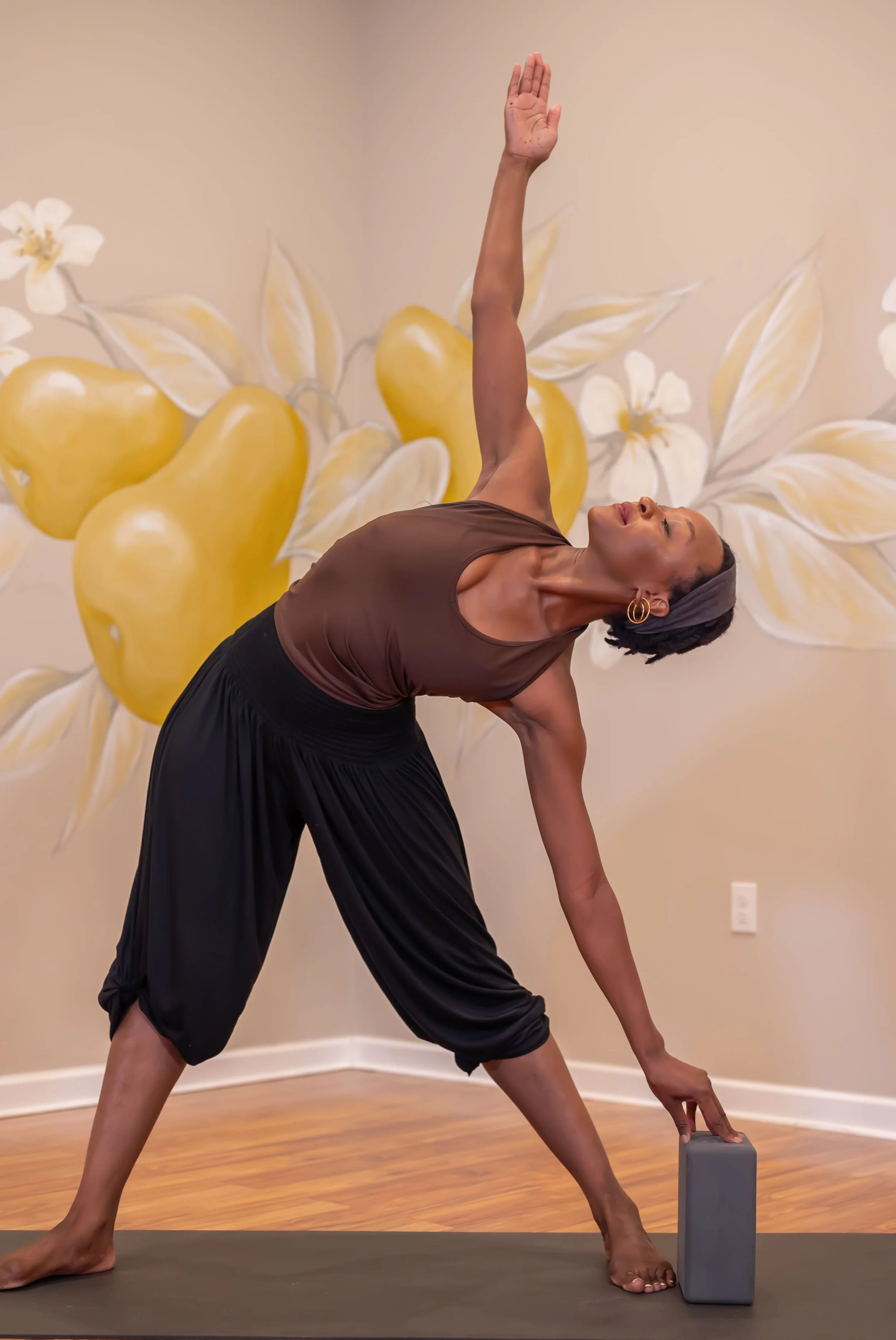 Woman practicing yoga bending to the side with hand on yoga block
