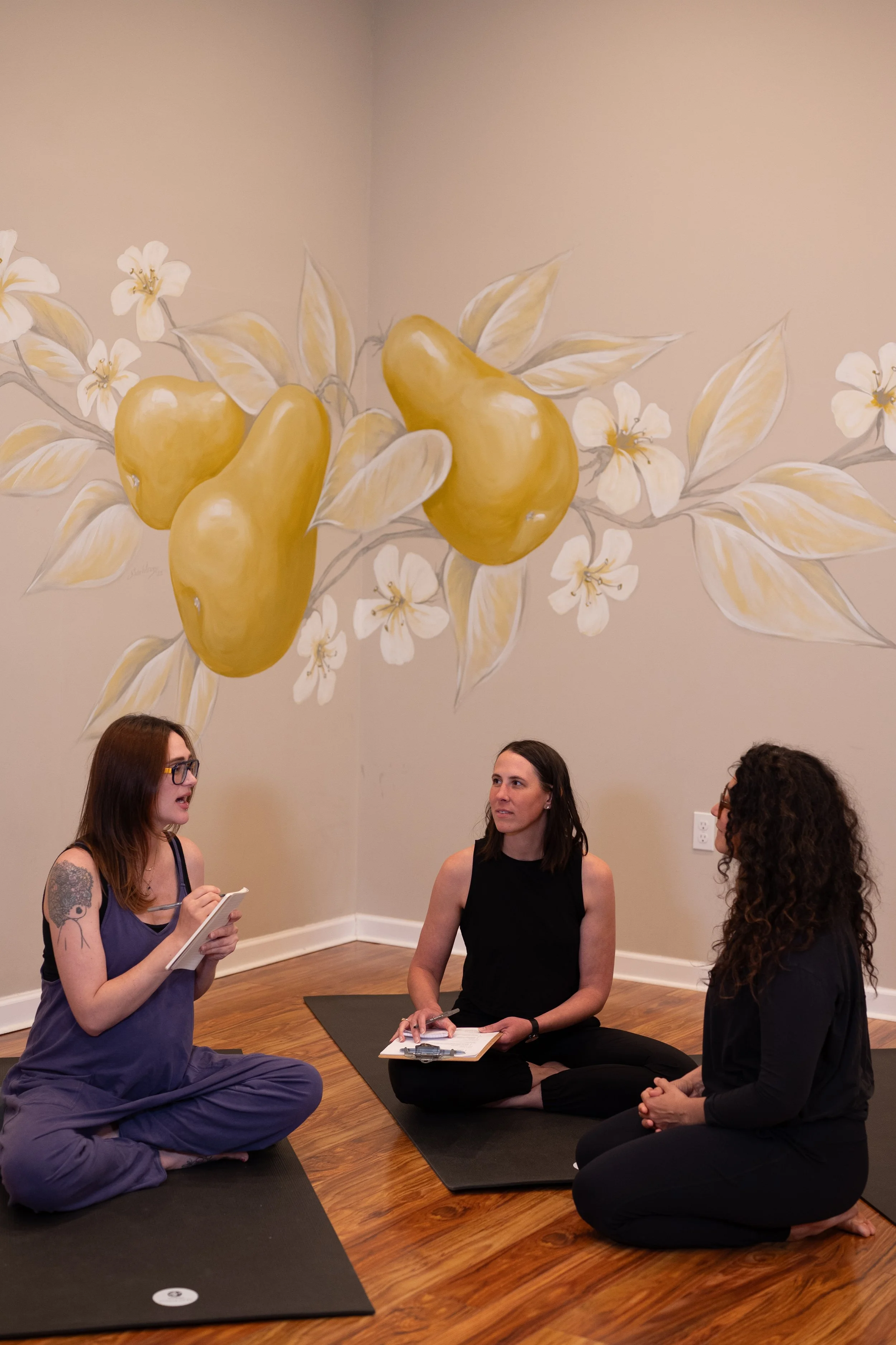 Three female yoga instructors sitting on mats talking
