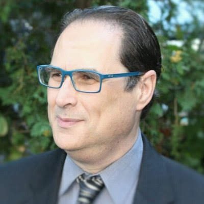 headshot of a man in a suit with glasses looking to the left