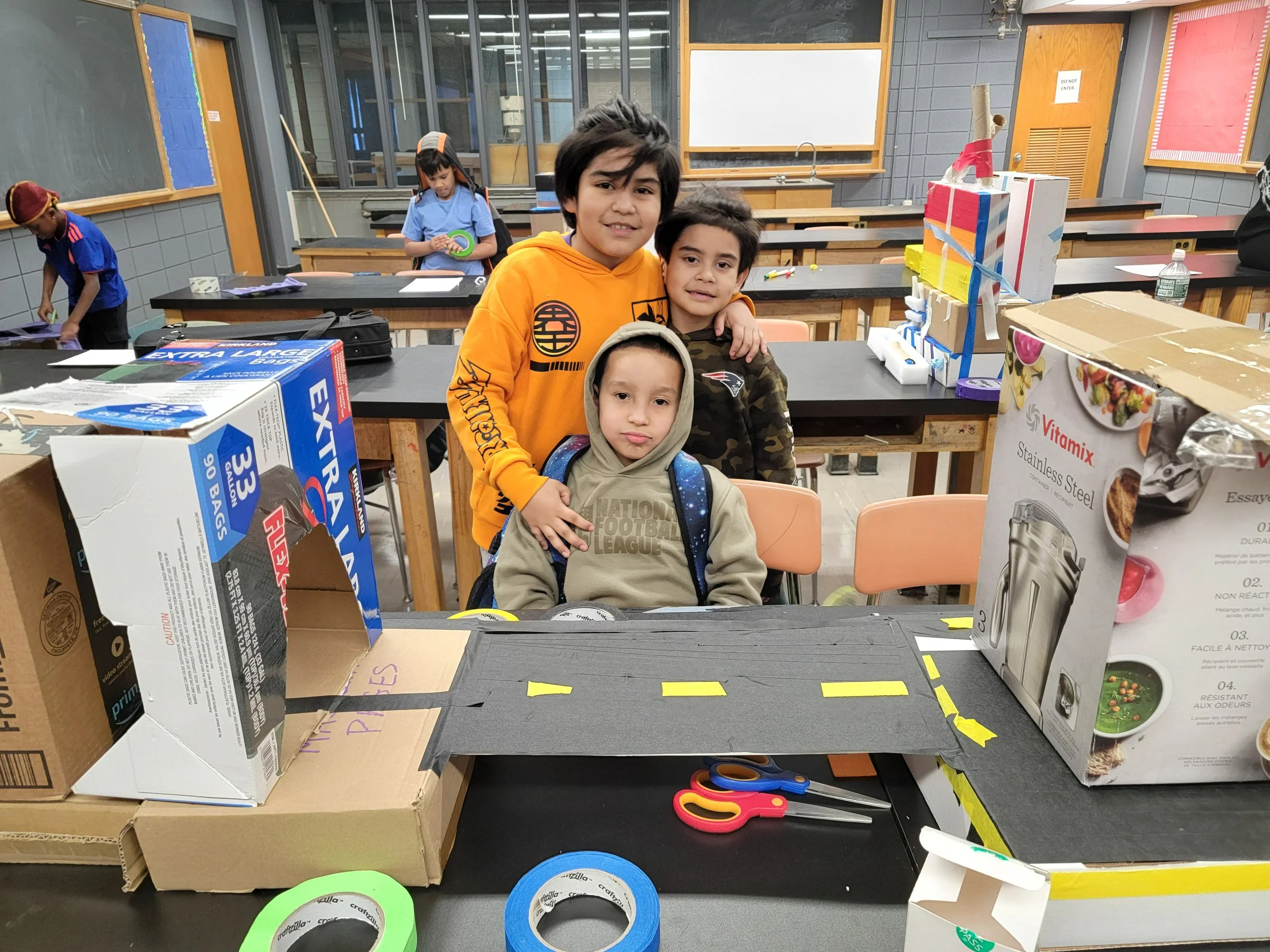 three youth posing infornt of their artwork and participating at A.L.E. on the road programming