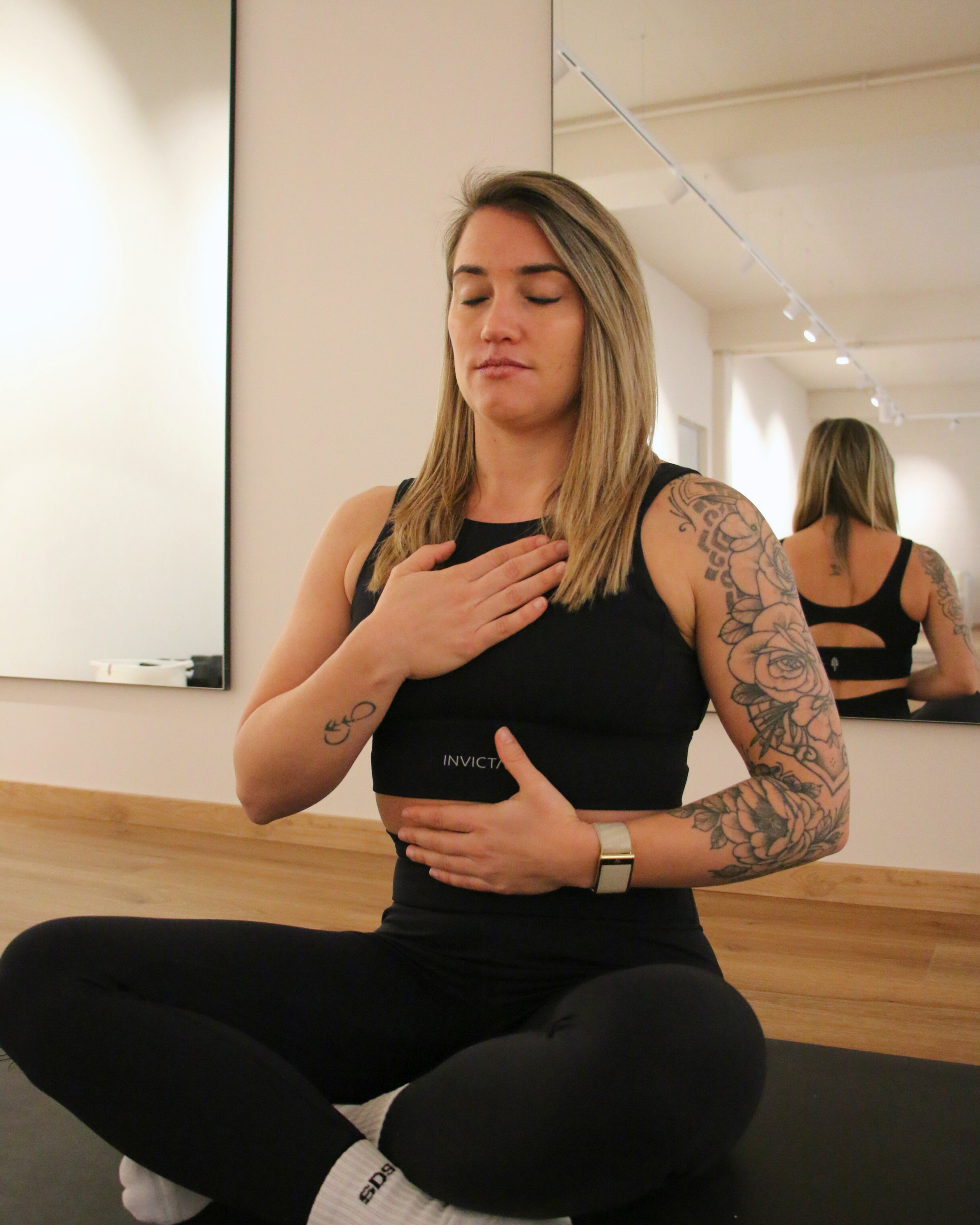 Drei lachende Frauen im Sonnenlicht, eine hält einen weißen Regenschirm und trägt einen Hut, die anderen tragen Brillen und einen warmen Pullover oder Mantel.