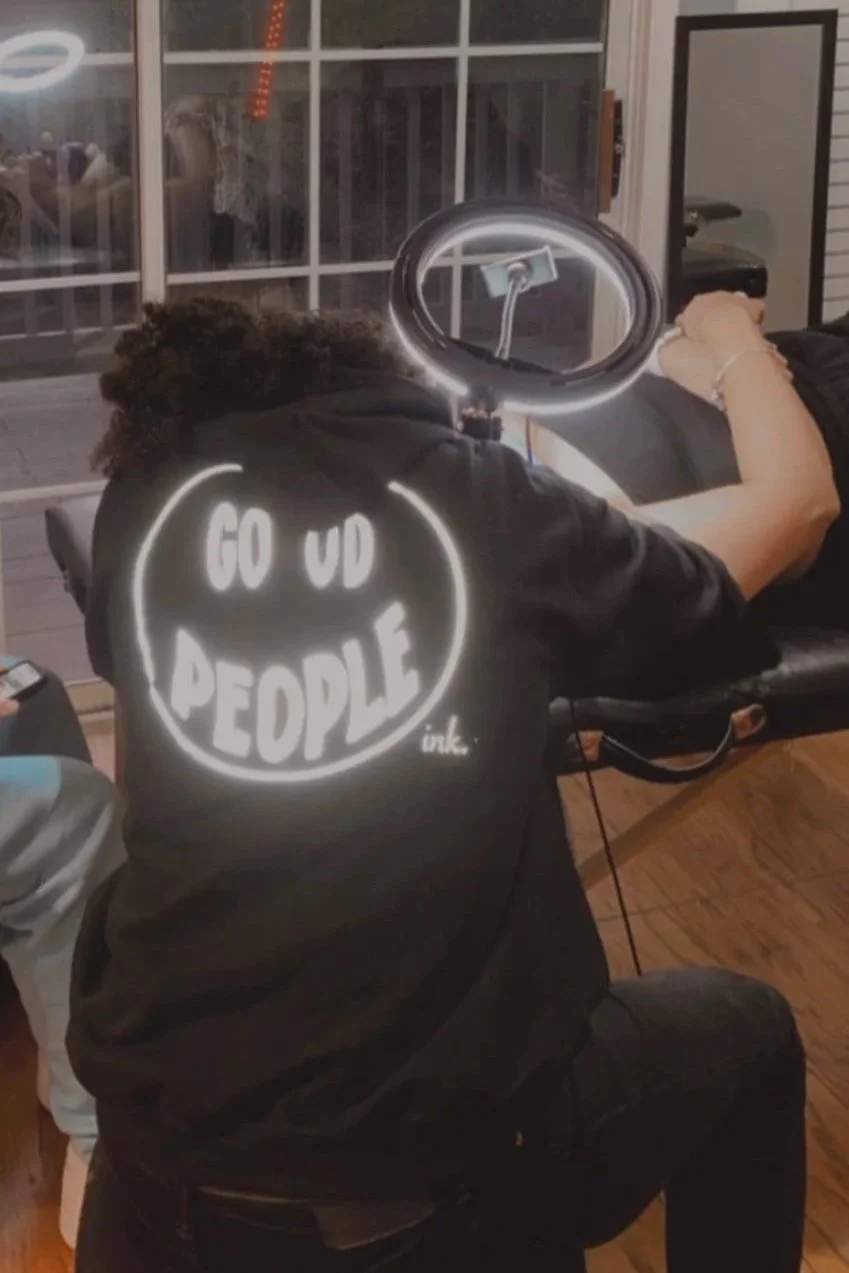 Artist wearing merch while tattooing during event