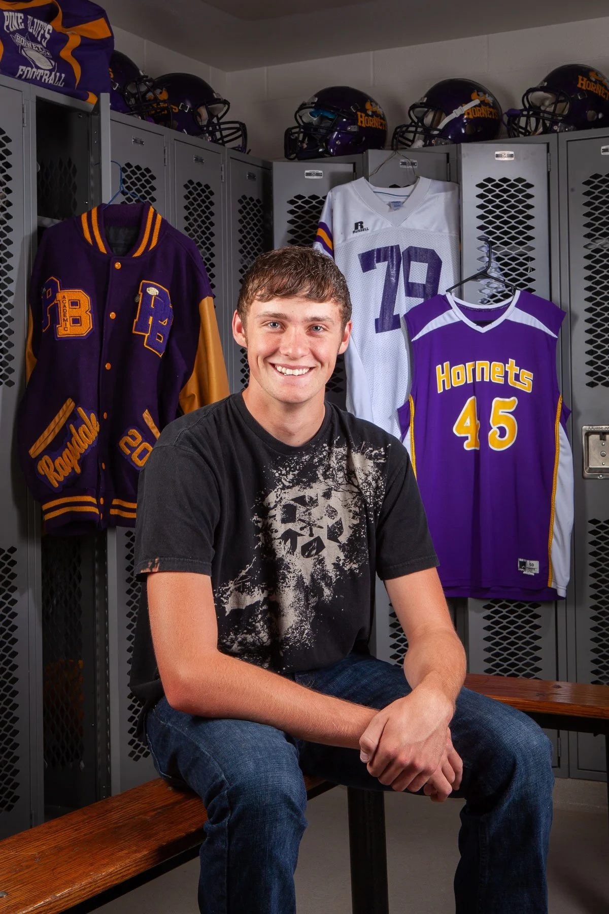 Senior portrait in the locker room with jerseys and a Letterman school jacket in Pine Bluffs, Wyoming.