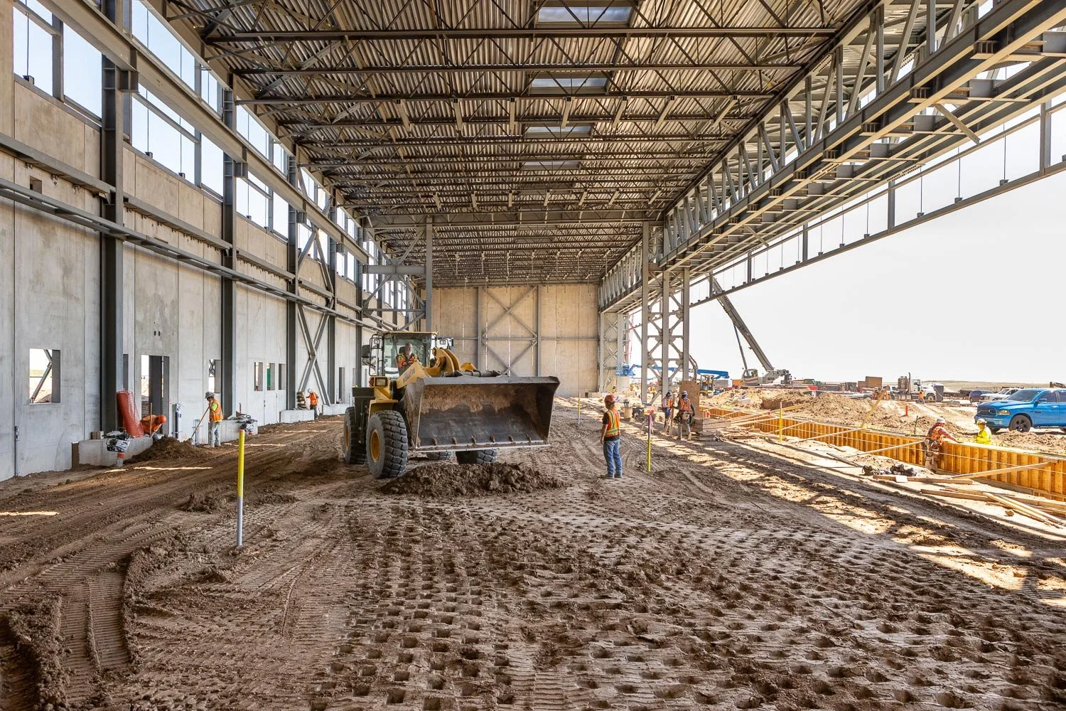 New building construction with a loader moving dirt on the floor of site.