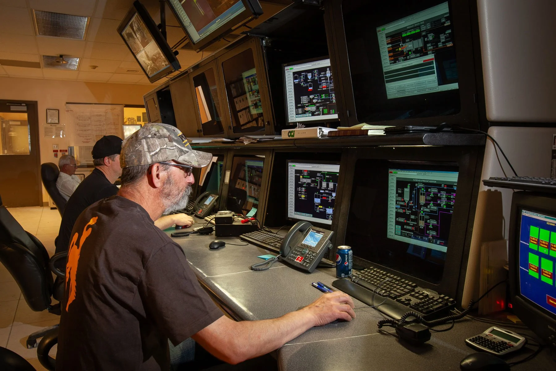 Workers watch computer screens in a control room at a trona mine.