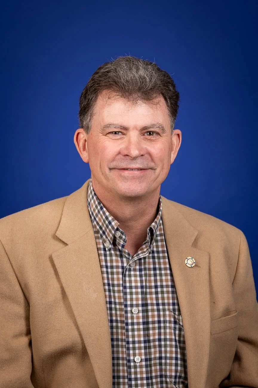 Business headshot portrait including a blue background.