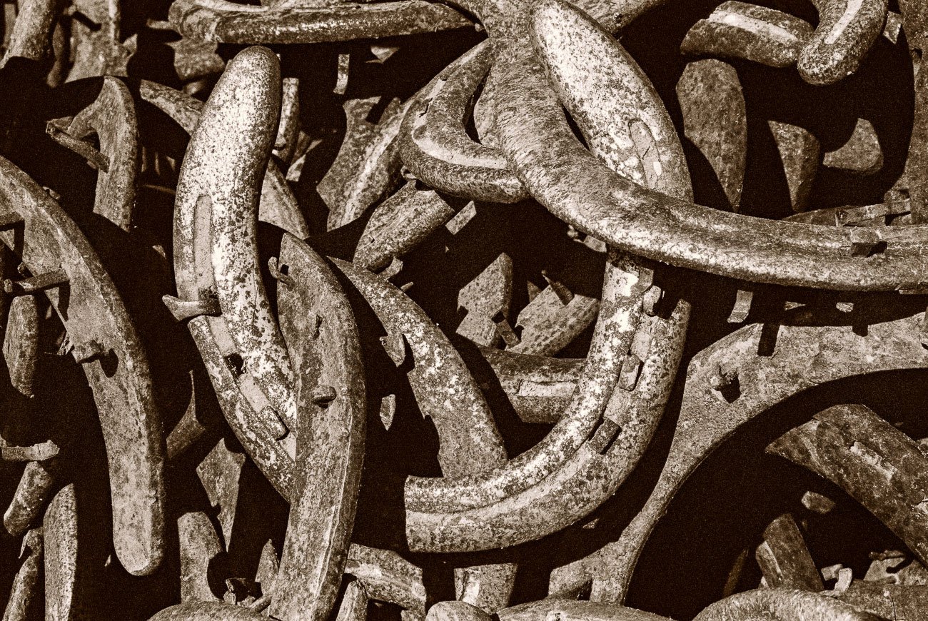 Pile of old, rusted horseshoes, sepia-toned image. Lucky horseshoes.