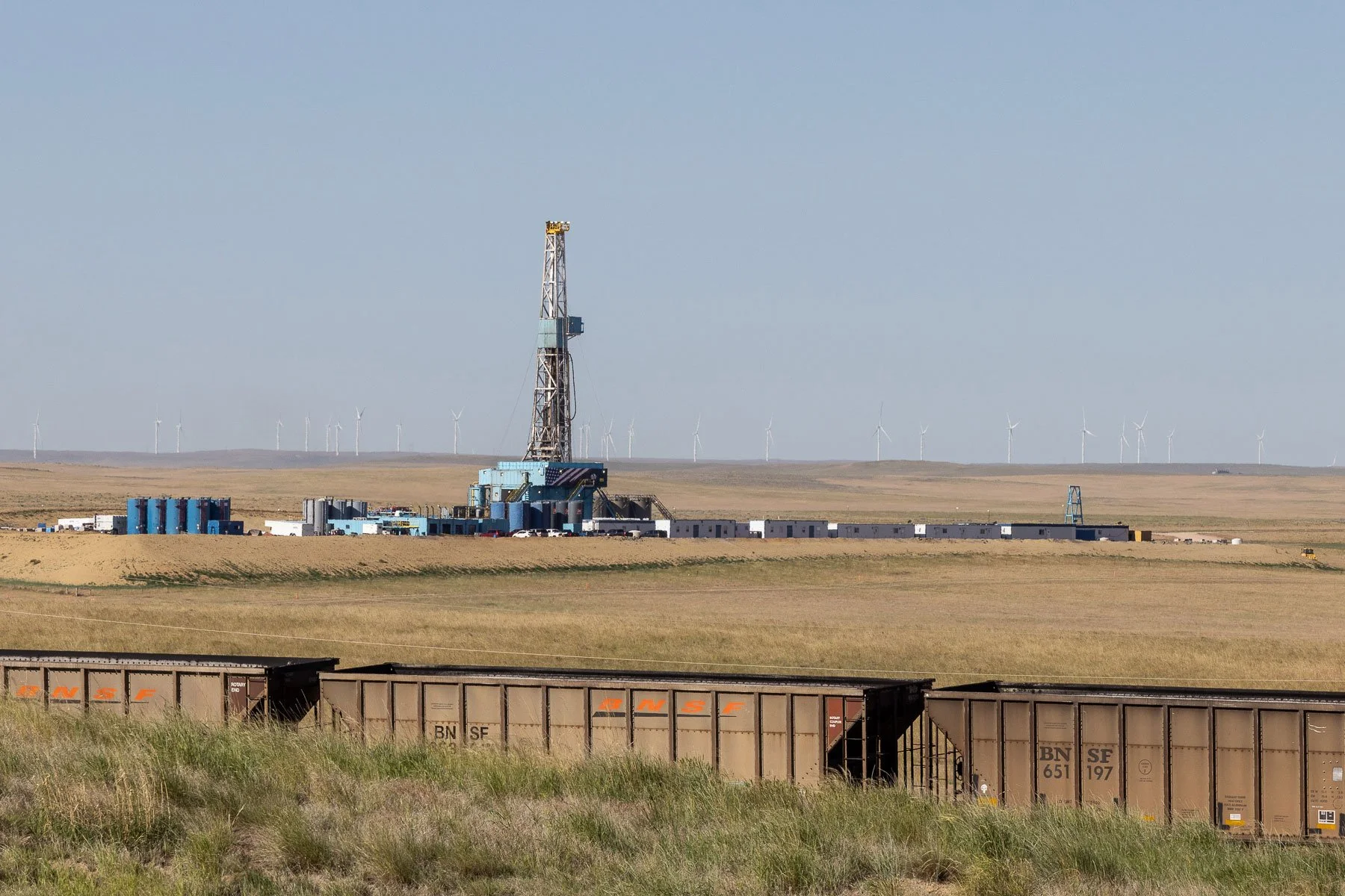 Coal train, oil and gas drilling rig, and windmills in the background near Gillette, Wyoming.