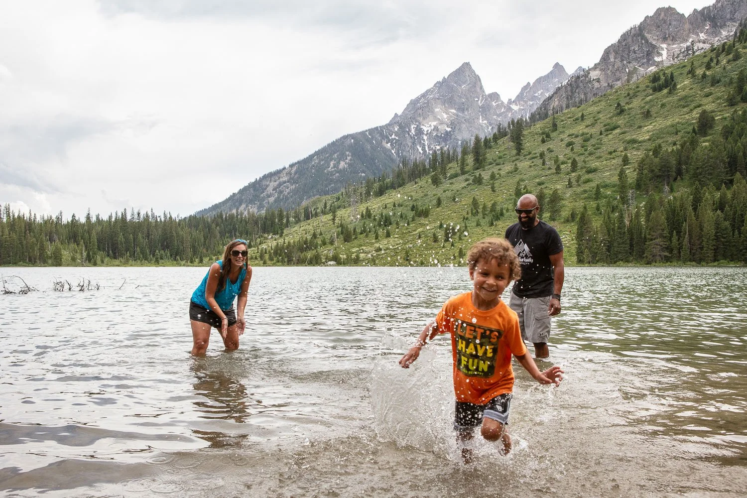 Lifestyle photography, including a day in the life of a family camping in an RV at Grand Teton National Park. Image created for Rev Group. Family playing in the lake.