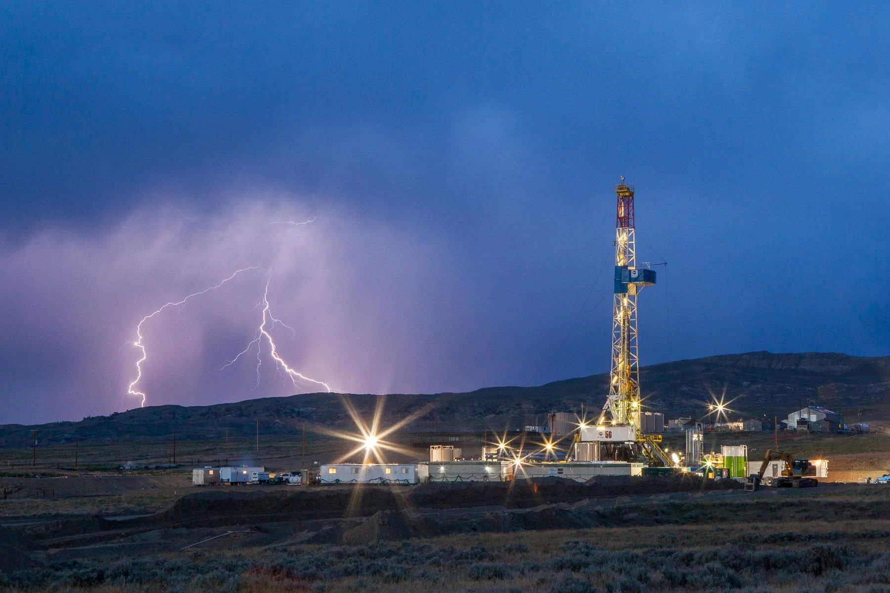 Thunderstorm and lightning strikes near an oil and gas drilling rig in central Wyoming.